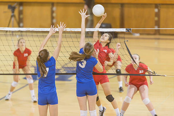 High school female volleyball player spiking the ball High school female volleyball player spiking the ball during a competitive game volleyball stock pictures, royalty-free photos & images