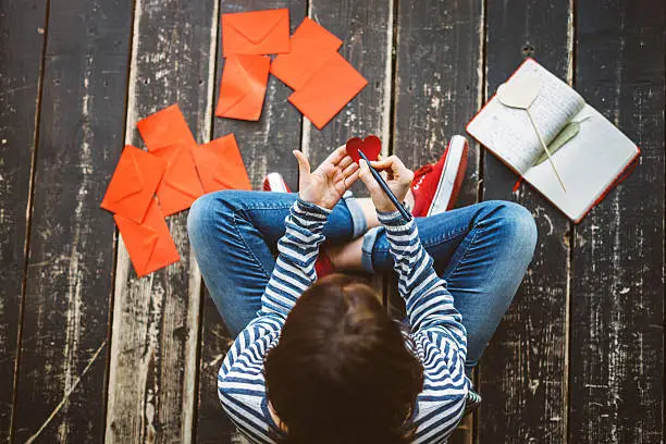 Photo of Young woman writing a valentine card - top view