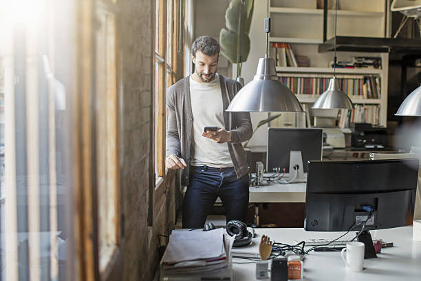 istock Businessman using mobile phone by window in office 639024642