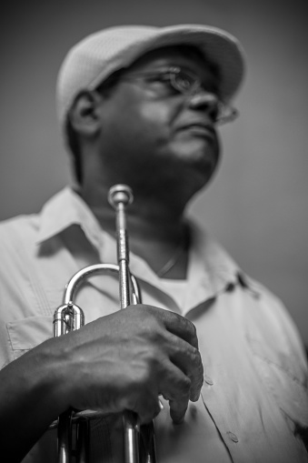 Havana, Cuba - October 9, 2016: Plaza Vieja in Old Havana on busy week day in November. Black Cuban musician holding his trumpet. Local cuban music band performing on the plaza corner (public place)  for visiting tourists and restaurants next door. Cuban music is famous all over the world. Perfect mix of Spanish, Afircan and South American ethnic sounds. Ever since the International success of \