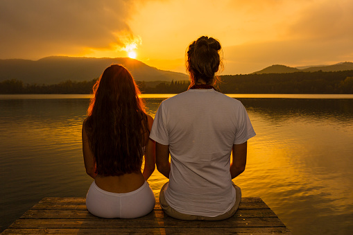 Young couple watching the sunset over lake