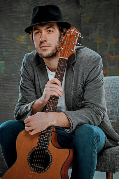 istock Cool guy sitting with guitar on gray background 639028542