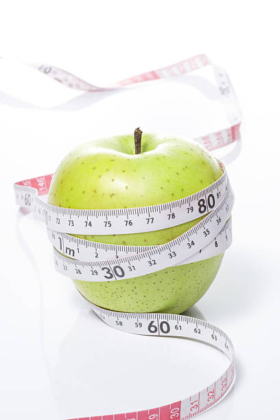 istock Green apple and tape measure on white background 639029344