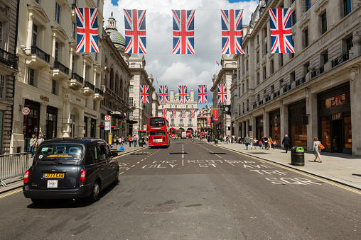 London, United Kingdom - June 24, 2016: The iconic Regent street flags with tourists  and a red bus and black cab in Piccadilly Circus late in the day.