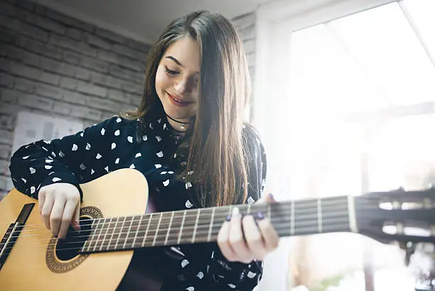 Photo of Young girl  practicing guitar.