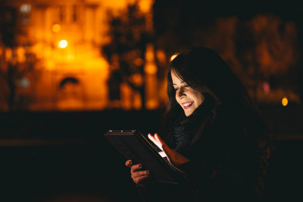 istock Young girl using tablet in the city at night 639036362