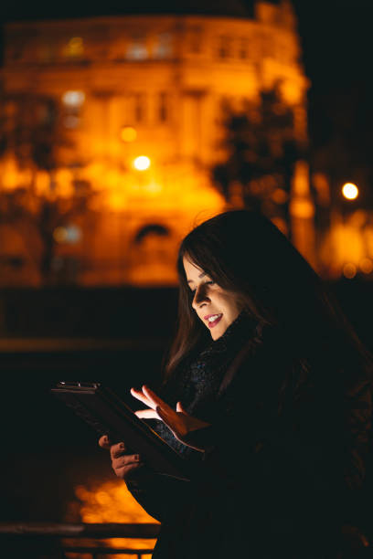 istock Young girl using tablet in the city at night 639037378