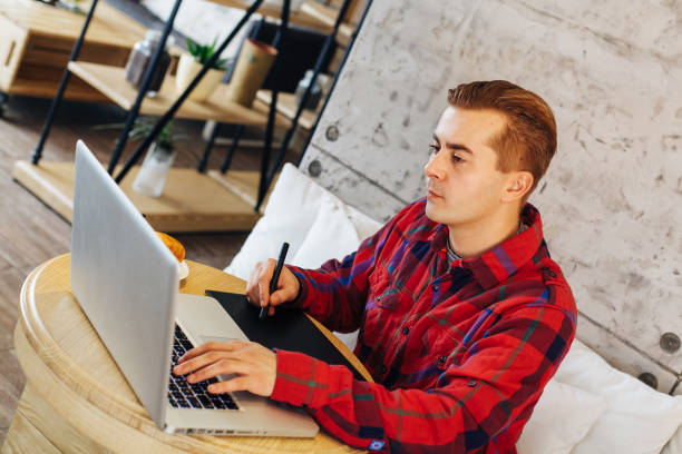 istock Young man designing on laptop in a cafe 639039442