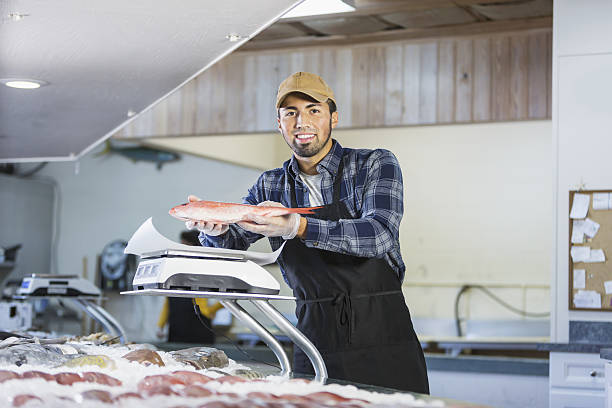 Hispanic man working in seafood market, holding fish