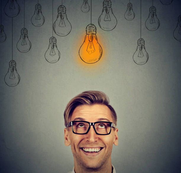 istock man in glasses looking up at bright light bulb 639056840
