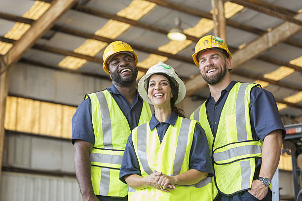 Construction crew with female boss Three multi-ethnic workers wearing hardhats and safety vests. The foreman is the Hispanic woman standing in the middle, laughing. Reflective Jackets stock pictures, royalty-free photos & images