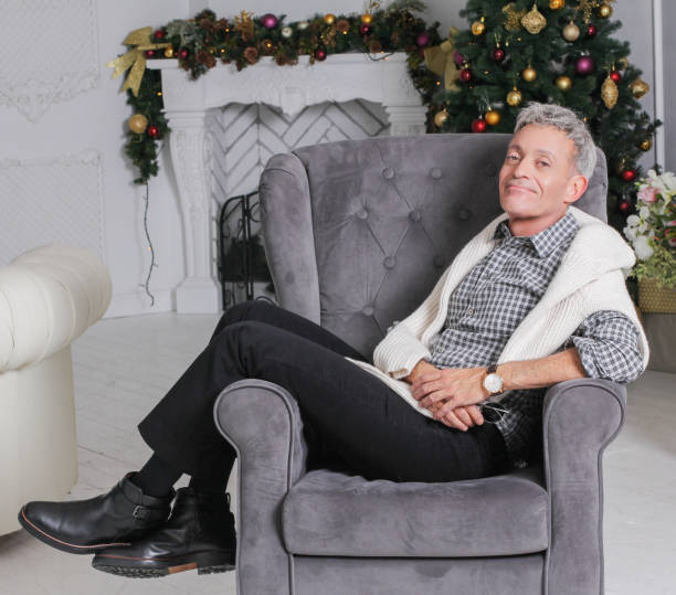 Man sitting in couch with christmas tree in background stock photo