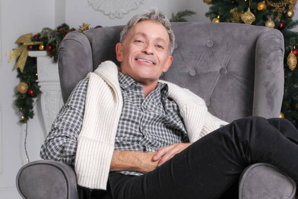 Man sitting in couch with christmas tree in background stock photo