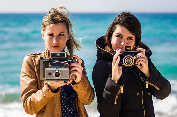 due ragazze in possesso di treo camera mare guardando bokeh - treo foto e immagini stock