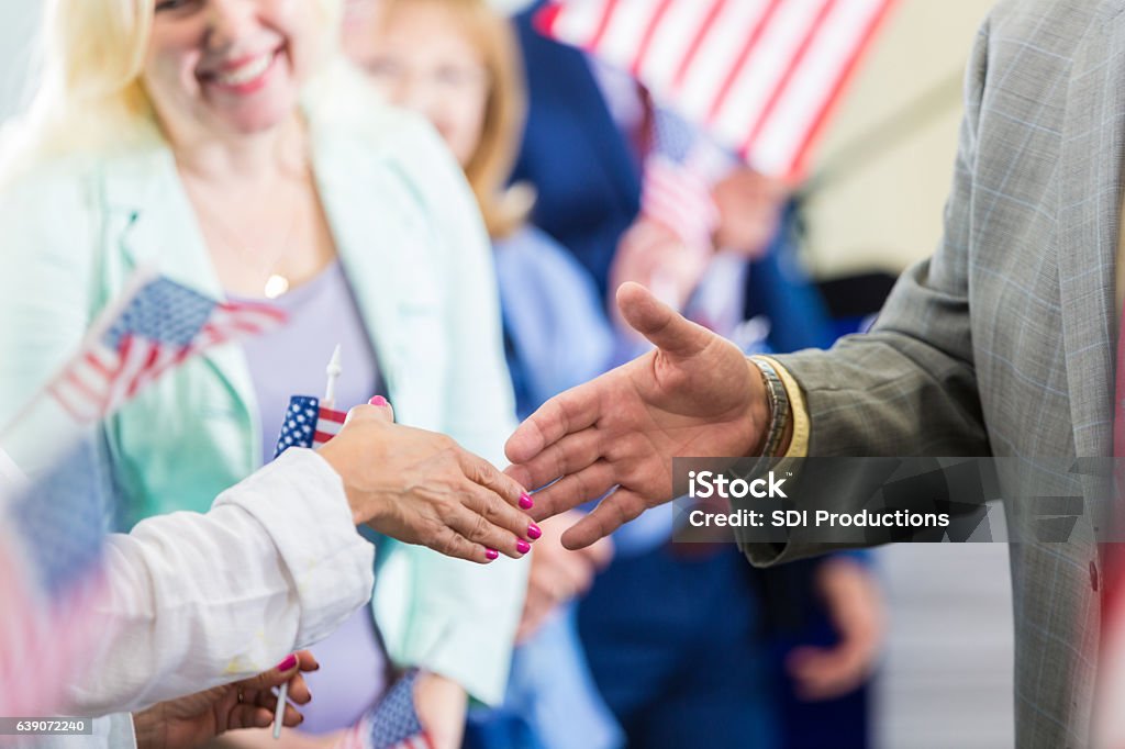 Political candidate greets supporters during rally Close up of political candidate shaking hands with a female supporter. Candidate Stock Photo