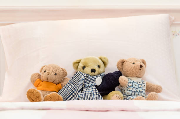 istock Teddy bears on a pink bed and pillows 639073194