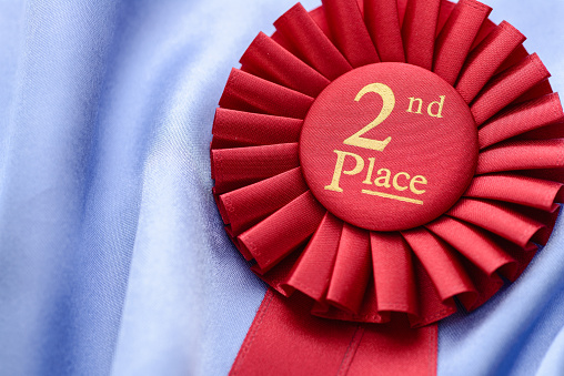 Close up of a textured fabric red 2nd place red rosette for the second placed winner in a competition or championship