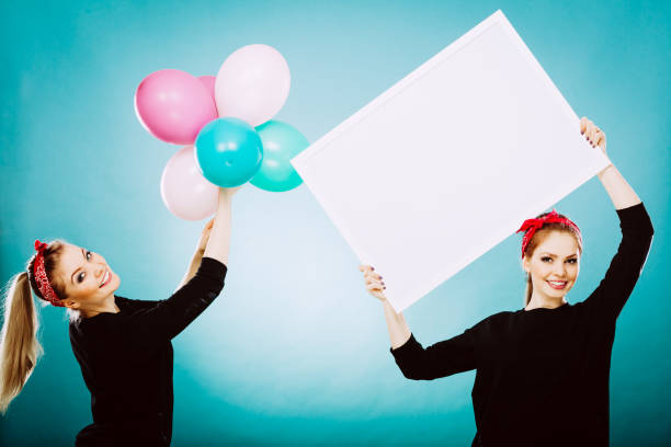 istock Two girls with blank board and balloons 639080658