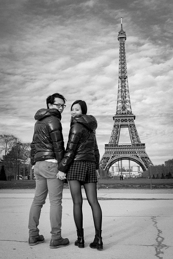 Couple in Paris by Eiffel Tower in black and white looking back