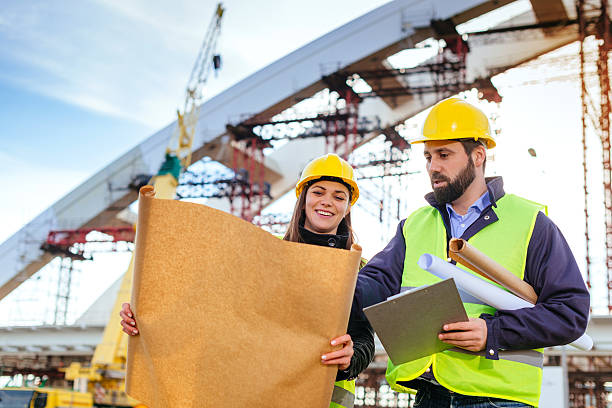 istock Engineers with hardhats and blueprints on construction site 639082972