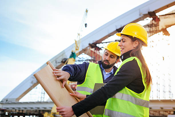 istock Engineers with hardhats and blueprints on construction site 639086250