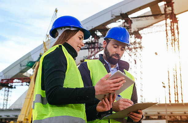 istock Architects with hardhats and blueprints on construction site 639086400