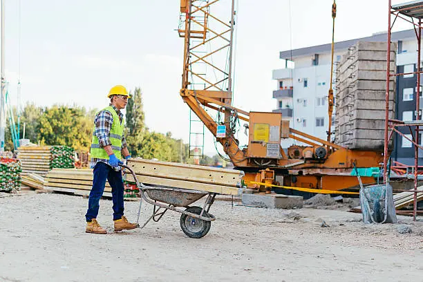 Photo of Consturction worker pushing wheelbarrow on construction site