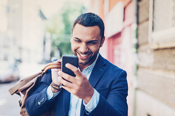 istock Smiling man with smart phone on the street 639095976