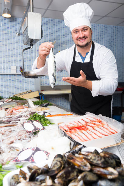 istock Cheerful seller shows hands fish on counter 639098552