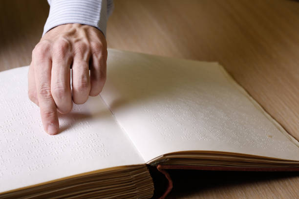 istock Blind person touching book, written in braille writing 639107934