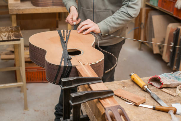 istock Serious professional guitar-maker working with unfinished guitar at workshop 639109458