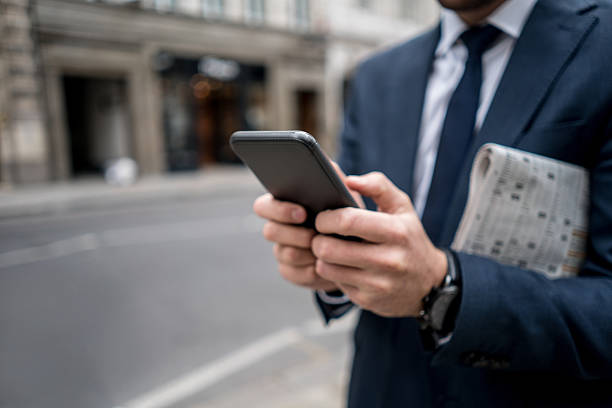 primo piano su un uomo d'affari che telefona al telefono - daily newspaper foto e immagini stock