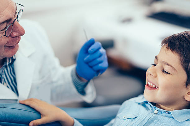 kleiner junge mit senior zahnarzt - human teeth little boys behavior expressing negativity stock-fotos und bilder