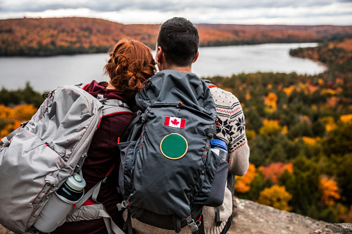 Young couple hiking in mountain and relaxing looking at view in the Algonquin Park, Ontario - Canada.