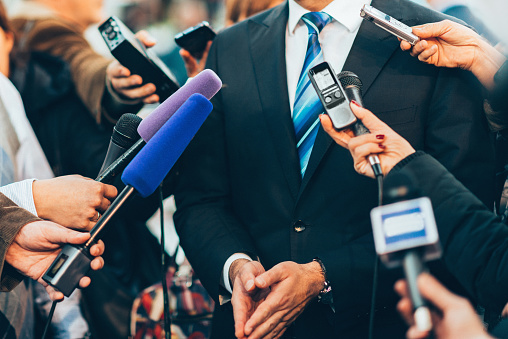 Hand holding a microphone on blue background.