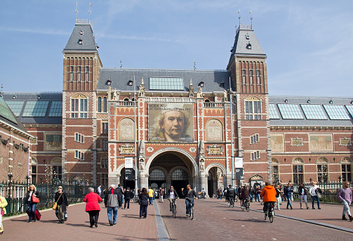 Amsterdam, Holland - April 10, 2015: Tourists and cylcists in front of the Rijksuseum with billboard of Rembrandt exhibition in Amsterdam, Holland on Apil 10, 2015