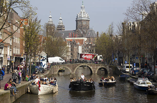 Amsterdam, Holland - April 10, 2015: Tourists in party boats in a canal in Amsterdam, Holland on Apil 10, 2015