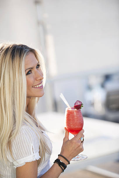 Woman with cocktail Happy young woman holding strawberry daiquiri fruit garnish stock pictures, royalty-free photos & images