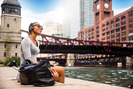 Woman in the city listening to music using wireless headphones.