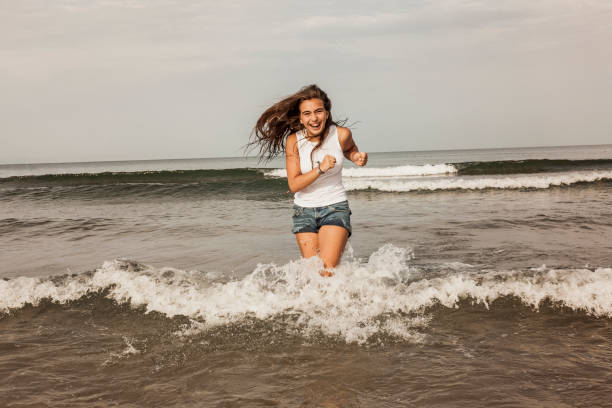 Happy teenager playing with the water at the seashore stock photo