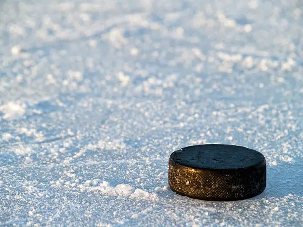 Hockey Puck on Ice at Outdoor Pond Ice Hockey Rink, with chewed up ice.