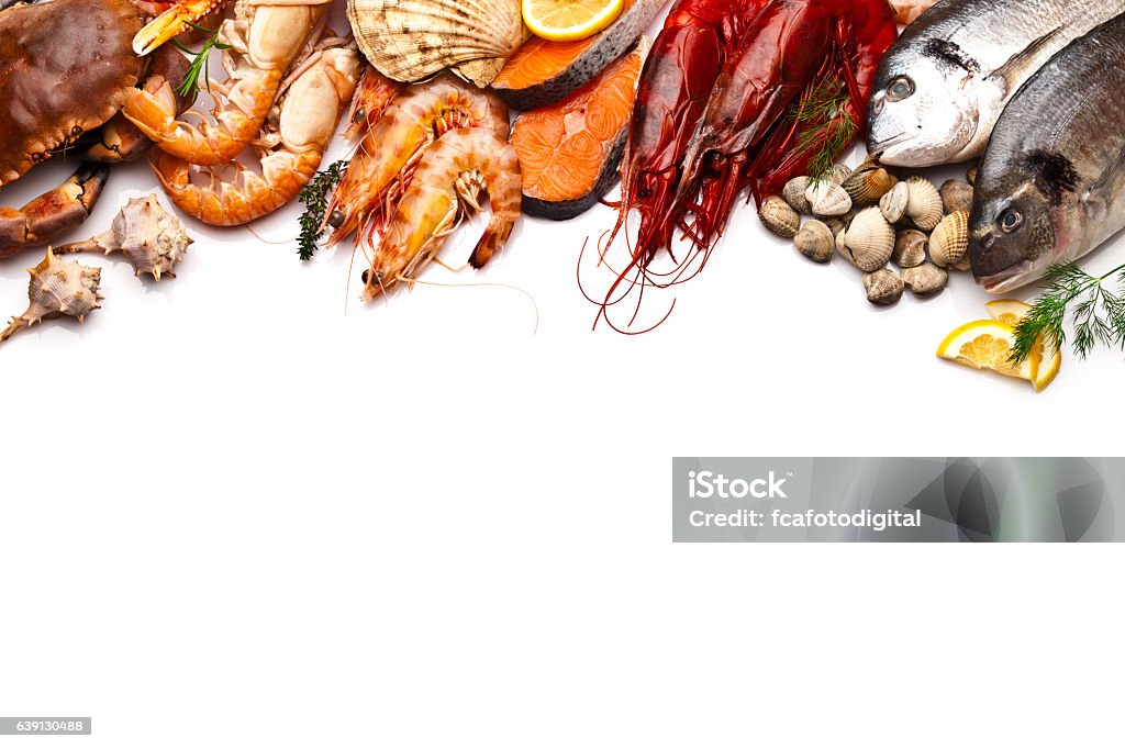 Seafood border with white copy space Border of different types of seafood including sea bream, mussel, crab, clams, salmon, shrimps, and prawns. Seafood is arranged at the upper border of the frame leaving a plenty copy space in the center and bottom of a white background. Colors are very vibrant and saturated. Shot directly above with DSRL Canon EOS 5D Mk II and Canon EF 70-200mm f/2.8L IS II USM Telephoto Zoom Lens Seafood Stock Photo