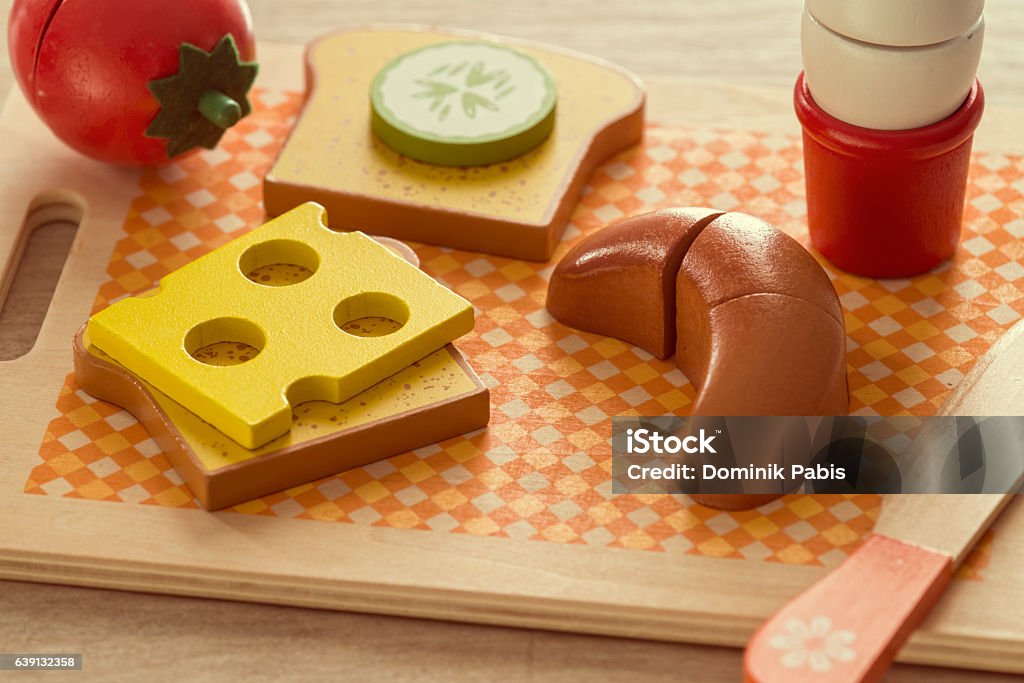 Breakfast, eggs, croissant, tomato, cheese, toast bread, funny retro style Close-up of breakfast including boiled egg, croissant, cheese, tomato, cucumber, toast bread, butter knife in funny vintage style using wooden toys. Composed on wooden cutting board. Boiled Egg Stock Photo