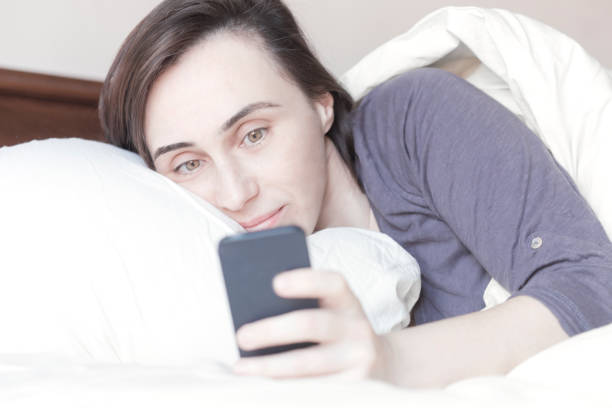istock Woman Lying on Bed Checking Her Phone 639138772