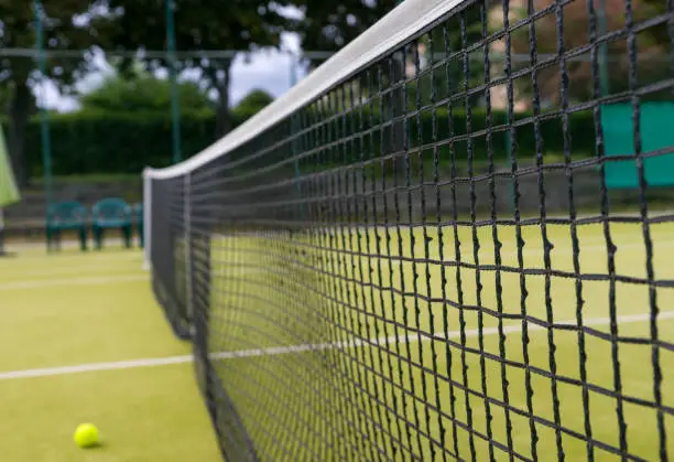 Tennis net and tennis-ball lying on the court outdoors  in summer or spring