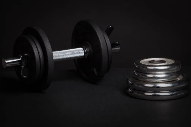 istock Dumbbell and barbell discs for workout on black background 639141098