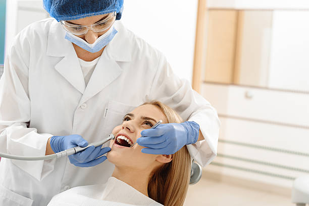 Odontologist drilling in mouth of client Stomatologist making standard procedure of cleaning cavities before starting removing strains. She holding dental instruments in her hands. Willing woman reclining on chair dental drill stock pictures, royalty-free photos & images