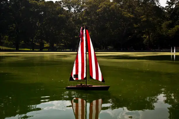 Sailing boat miniature remote-control in lake. Reflection in the water