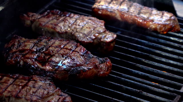 Two videos of opening the grill with steaks-real slow motion
