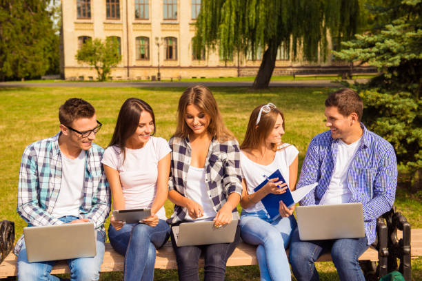 istock happy five diverse classmates sitting on bench and study up 639152334